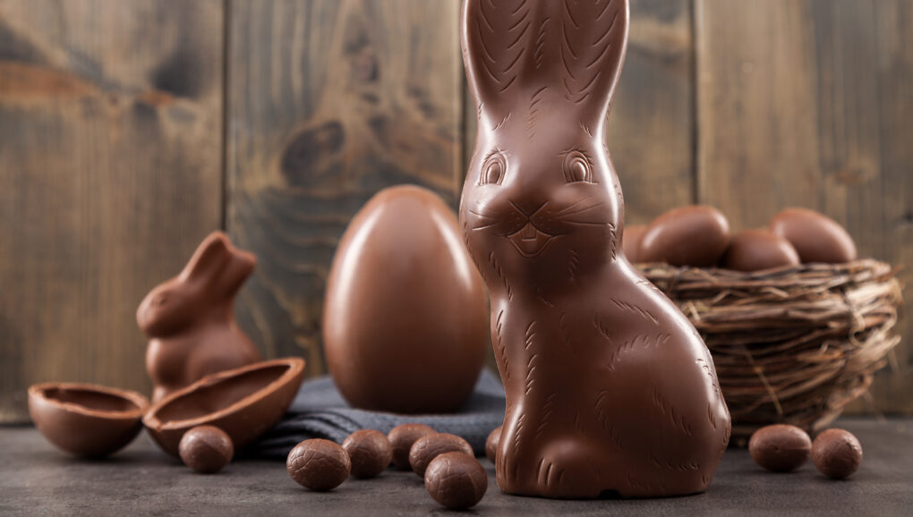 Chocolate Easter bunny, eggs and sweets on rustic background