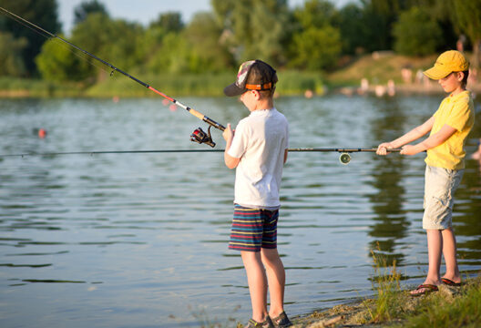 Two boys are fishing on the beach at sunset